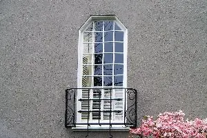 Custom specialty-shaped wood window in a stucco exterior
