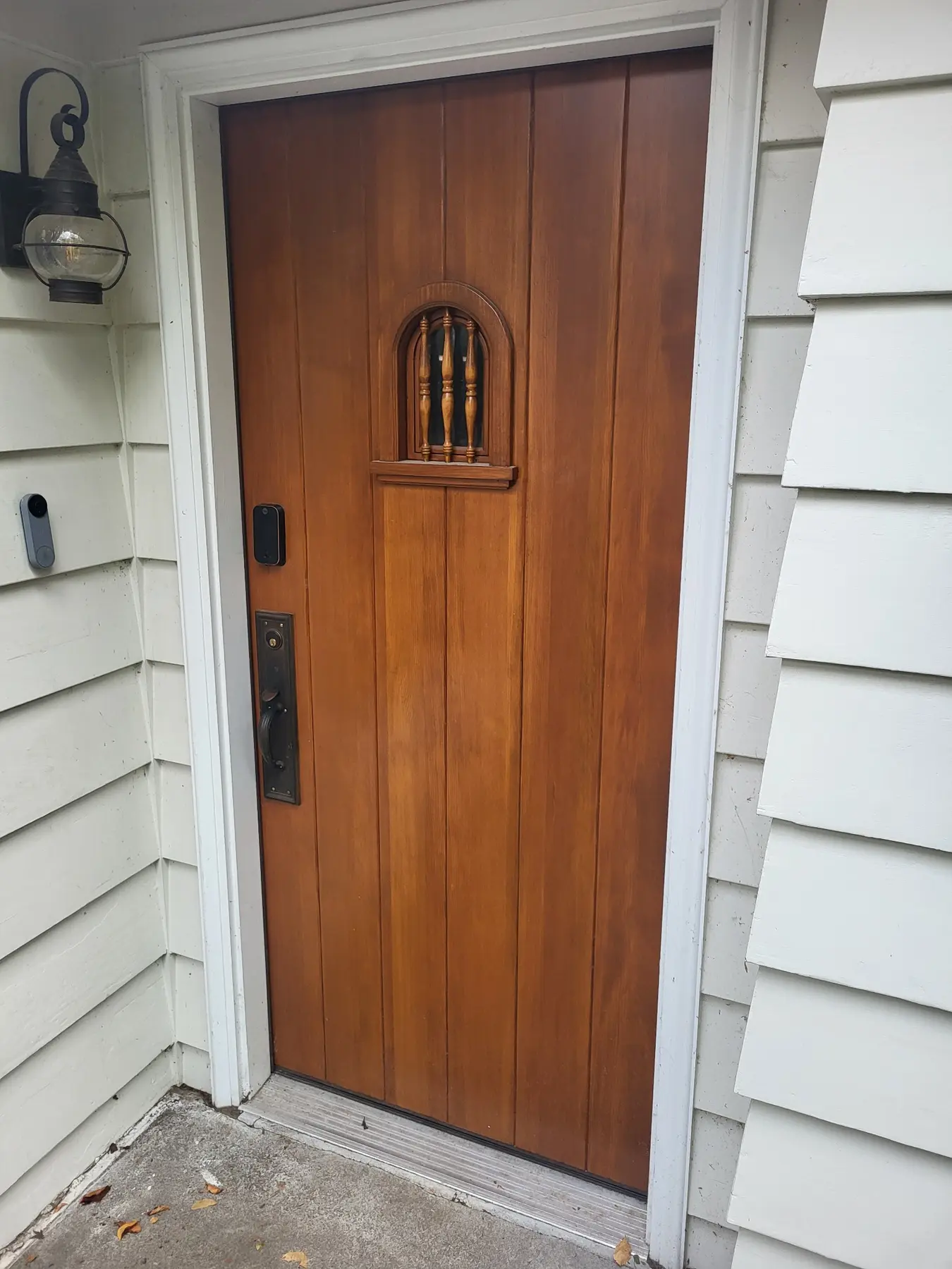 Installed custom vertical-grain wood entry door with an arched spindle detail