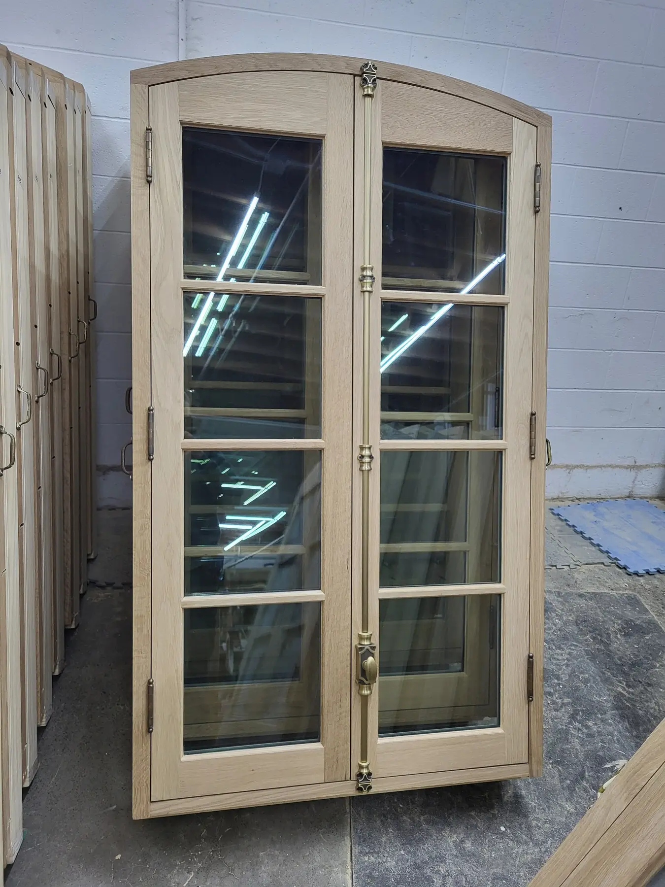 Curved-top paired wood casement windows prepared for restoration